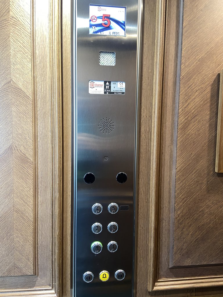 Ascensor con botones en braille y altura adecuada.