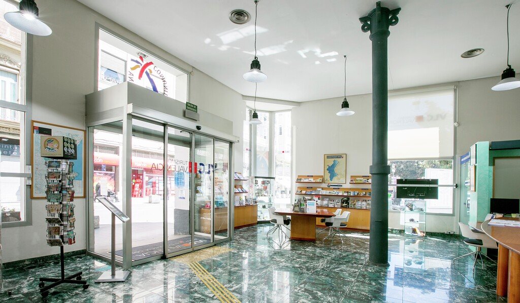 Interior de la oficina de turismo con área de descanso y señalización en el suelo.