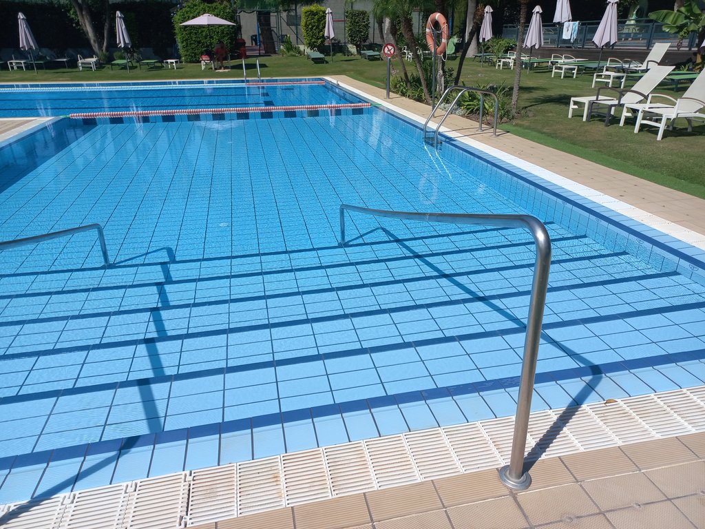 Acceso a piscina mediante escaleras con pasamanos.