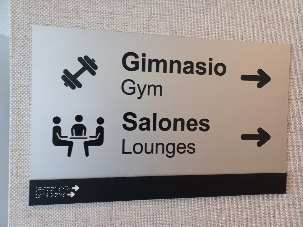 Retolació amb composició de text, pictograma, indicador direccional i braille.