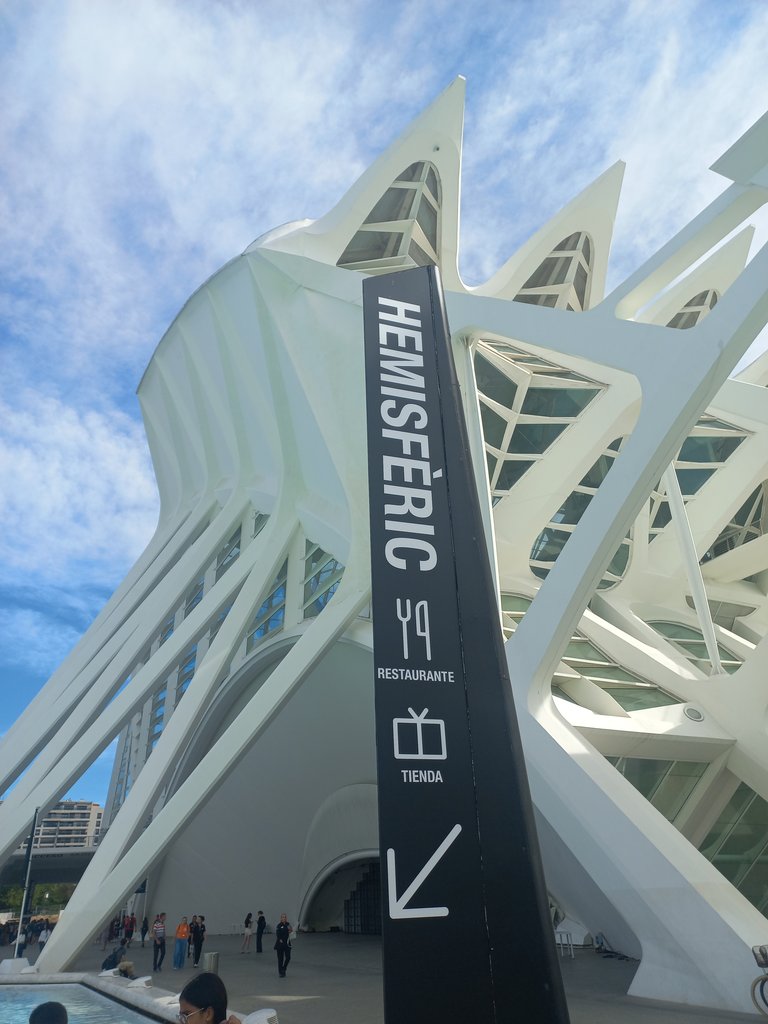 Señalética exterior con texto, pictograma e indicador direccional.