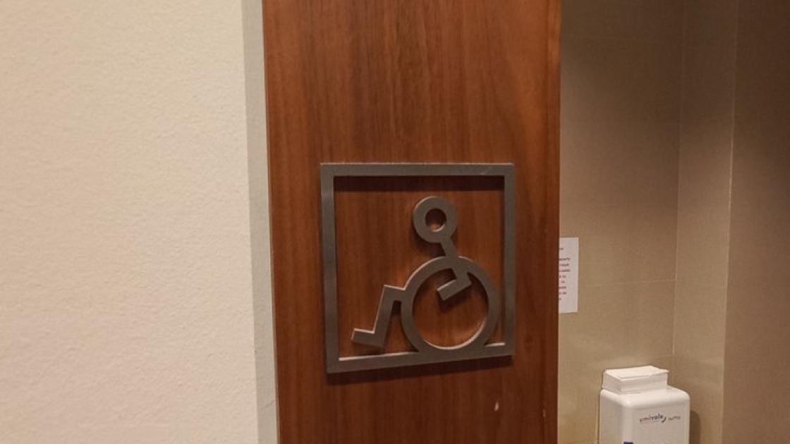 Baño adaptado señalizado mediante pictograma en alto relieve