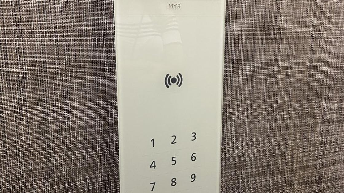 Elevator with lighted buttons and informational panel by floors.