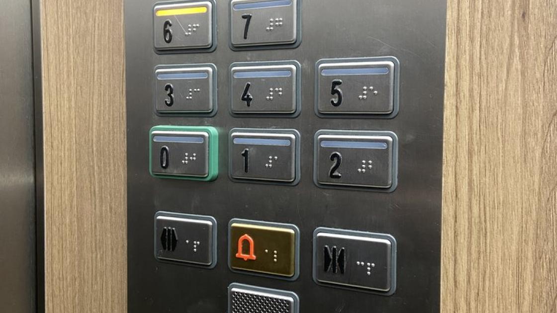 Accessible elevator with control panel at appropriate height and braille and illuminated buttons.