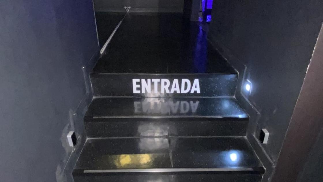 Senyalització d'entrada, mitjançant escales il·luminades, a un altre espai diferent.
