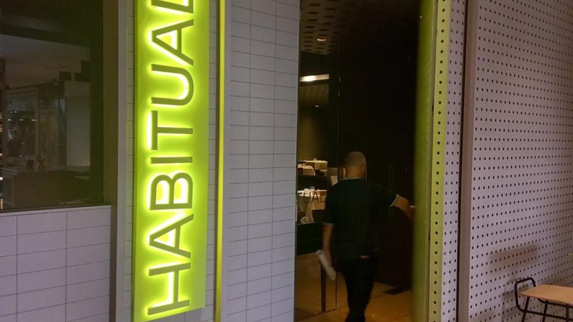 Establishment identified from the outside with a sign and directional indicator.