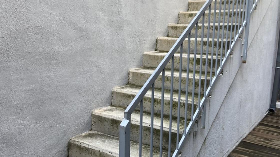 Stairs to access another activity space, with a support handrail.