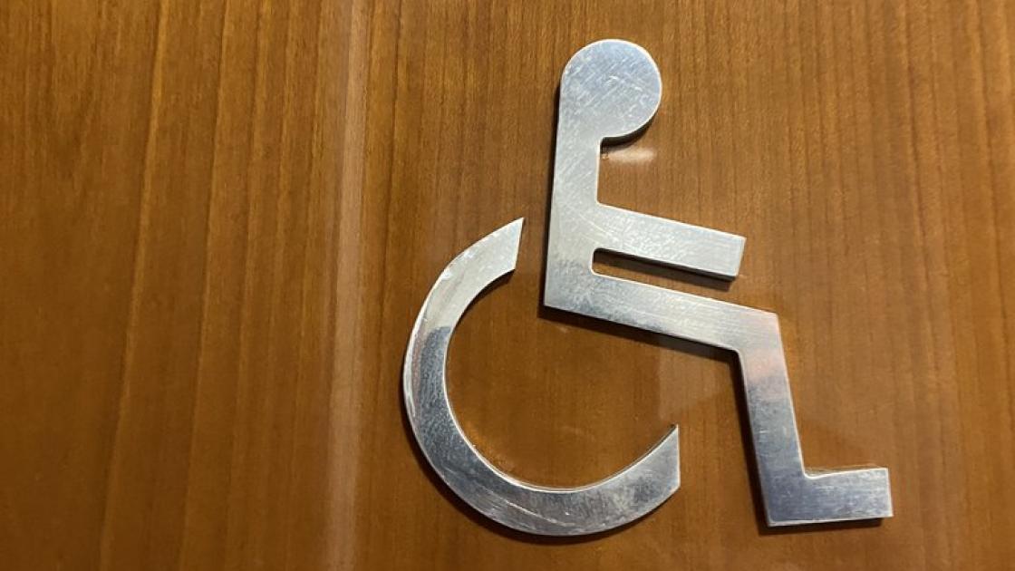 Signage for common adapted bathroom next to the access door.