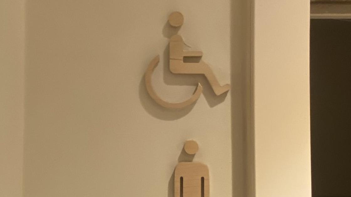 Señalización baños adaptados comunes en alto relieve.