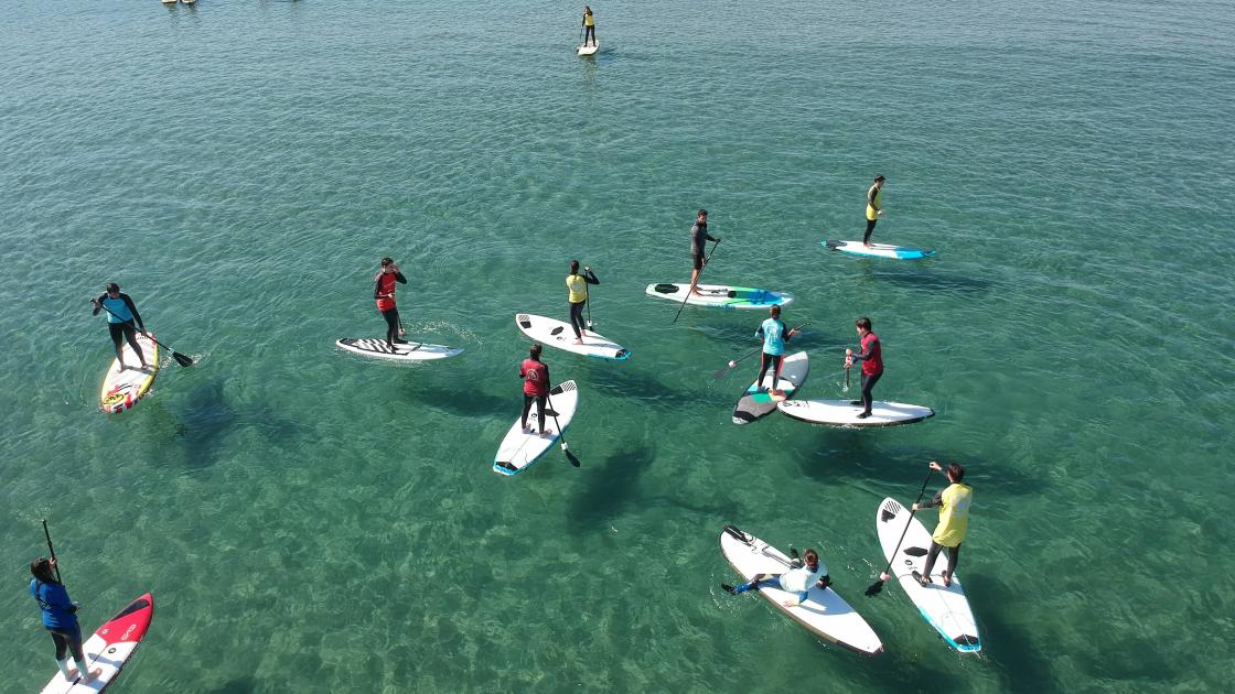 turistas practicando paddle surf en la playa