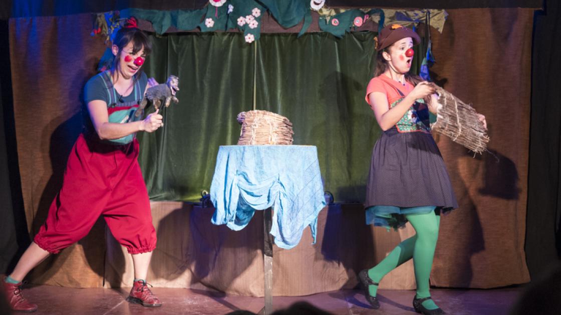Dos actrices disfrazadas interpretando encima del escenario,