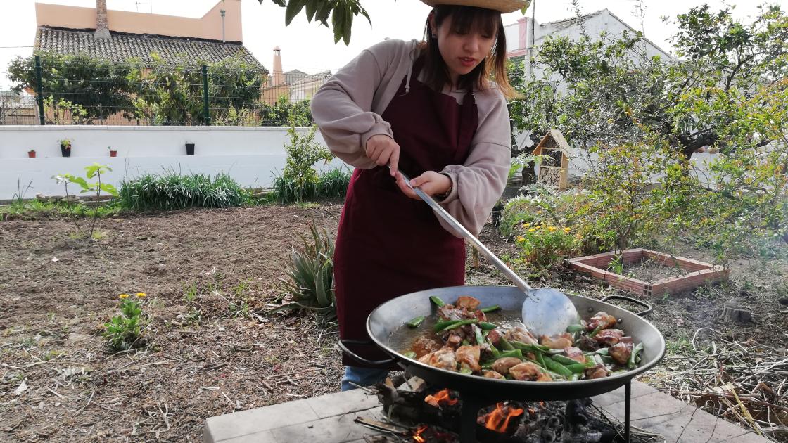 Turista aprendiendo a hacer una paella en la huerta