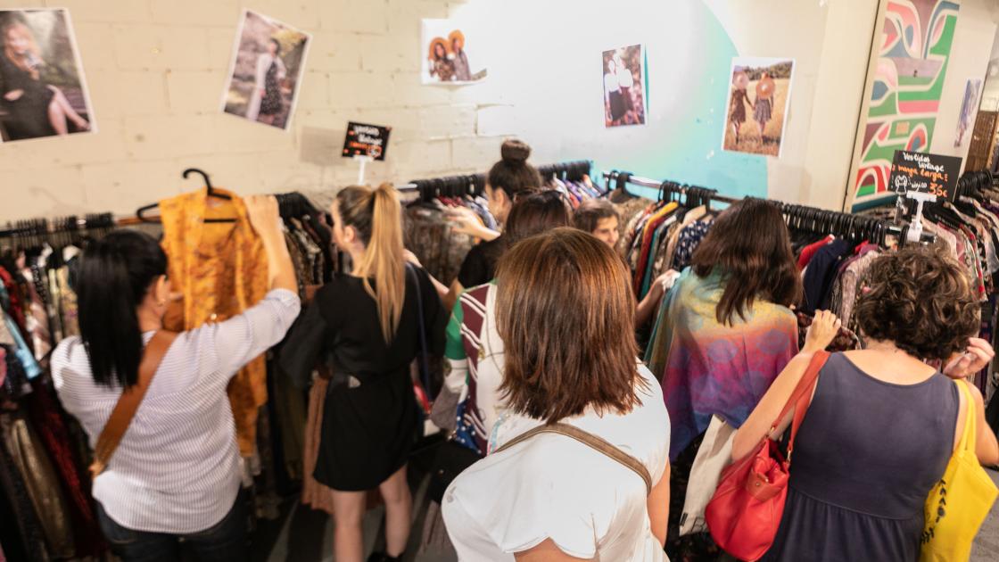 personas mirando ropa en mercadillo